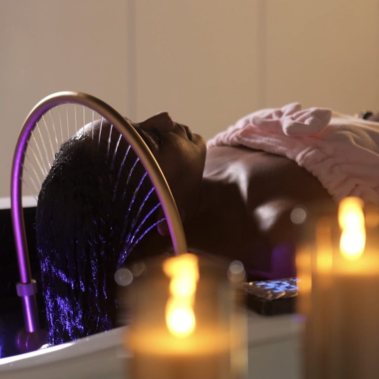 Femme allongée avec un bandeau sur les yeux, recevant un soin au spa.