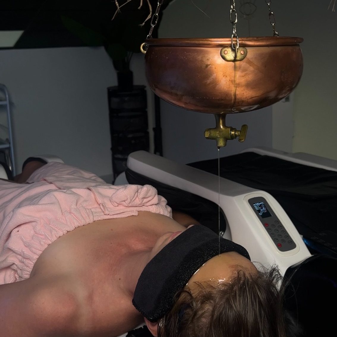 Femme allongée avec un bandeau sur les yeux, recevant un soin au spa.